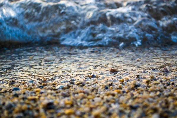 Welle in Küstennähe, eine Küste aus feinem Sand und Kieselsteinen. — Stockfoto