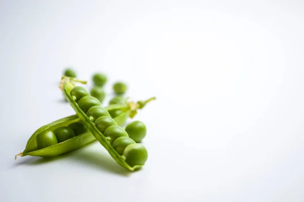 Frische grüne Erbsenschoten und grüne Erbsen mit Sprossen auf weißem Holzgrund. Konzept der gesunden Ernährung, frisches Gemüse. — Stockfoto