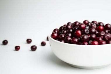 Beyaz arka planda kirazlar, beyaz bardağın yanında kirazlar..