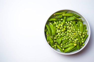 Beyaz arka planda izole edilmiş bir kasedeki taze bezelyeler.