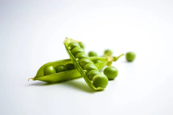 Grüne reife Erbsen, grüne Bohnen auf weißem Hintergrund, vegetarisches Essen aus nächster Nähe — Stockfoto