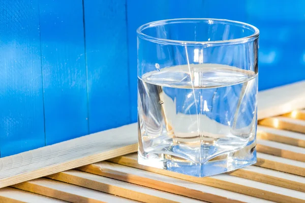 Вода в стекле, на синем фоне — стоковое фото