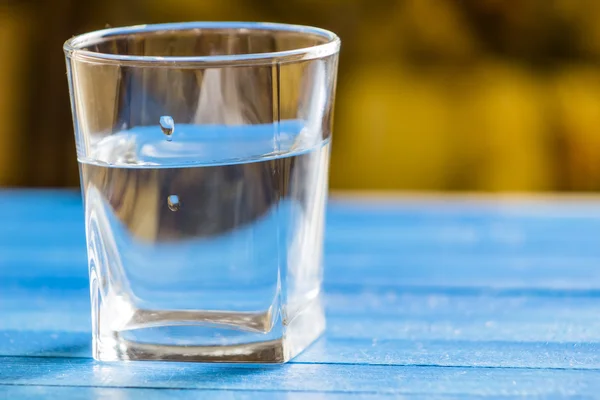 Вода в стекле, на синем фоне — стоковое фото