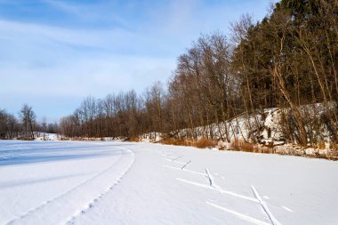 Güneş, kar ve kayak yolu donmuş bir gölü geçiyor. Kış sporu