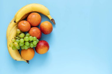 Mavi arka planda portakallar, muzlar ve üzümler. Sağlıklı ve taze meyveler.