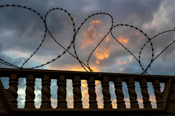 Συρματοπλέγματα σε ένα φράχτη ενάντια σε ένα δραματικό σκοτεινό ουρανό. — Φωτογραφία Αρχείου