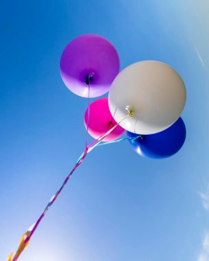 Mavi gökyüzüne karşı helyum dolu çok renkli şişme balonlar..
