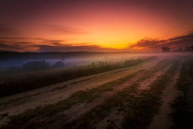 Çiçekli çayır ve güneş doğarken gökyüzünde görkemli bulutlar olan yaz manzarası. Yaz sabahı.
