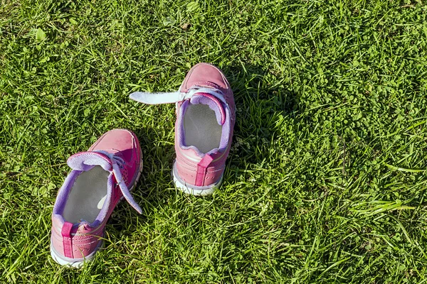 Draußen im Gras rosa Turnschuhe. Löwenzahn im Fokus. — Stockfoto