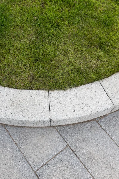 Pedra cinza pavimentação & kerb adjacente ao gramado de grama verde — Fotografia de Stock