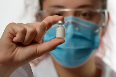 Doktor ya da bilim adamı, aşı şişesiyle el ele verdi.