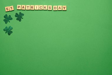 Ahşap harfler Aziz Patrick günü ve yeşil arka planda yeşil yoncalar, metin için üst görünüm yeri anlamına geliyor.