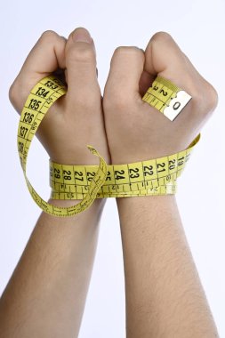 Diyet konsepti ve kilo kaybı. Beyaz bir arka planda sarı mezura ile bağlanmış iki kadın eli.