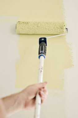 Açık yeşil renkli bir duvarı boyayan bir adamın fotoğrafı.