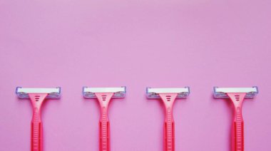 Pembe arka planda birkaç pembe tıraş bıçağı var.