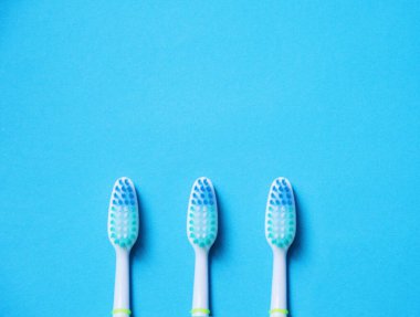 Mavi arka planda üç mavi diş fırçası.