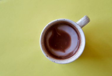 Sarı arka planda bir fincan sıcak çikolata resmi.