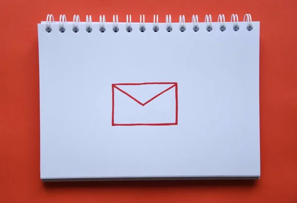 Photo of a drawing of red letter on white paper of a notebook on red background