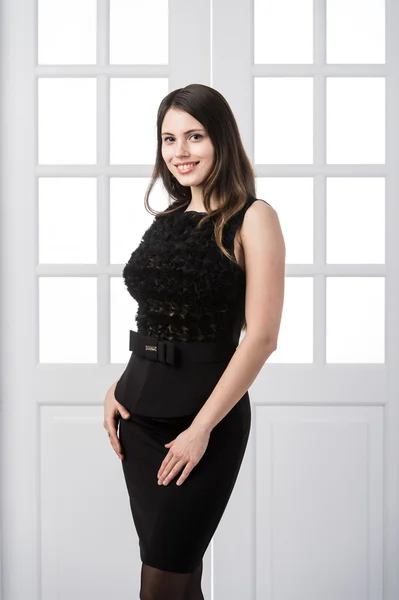Alegre modelo de moda vestido negro posando y sonriendo en estudio loft casa interior puertas detrás de — Foto de Stock