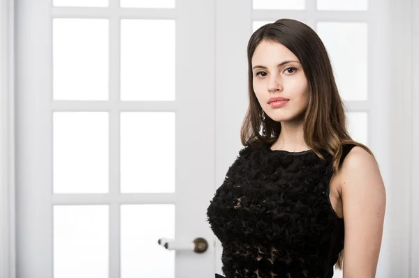 Hermosa mujer de pie en un vestido negro sobre el estudio loft casa puertas interiores detrás de — Foto de Stock