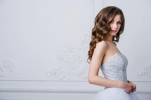 Close portrait of beautiful smiling bride woman with long curly hair posing in wedding dress at interior and smiling. Beauty indoor portrait. — Stock Photo, Image