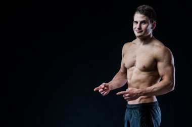 Gömleksiz kas atletik adam boş copyspace için iki el ve parmak ile noktası. Seksi vücut geliştirmeci siyah izole arka plan kopyalama alanı vücudunu gösteren.