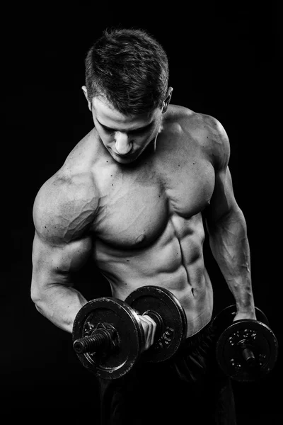 Contraste preto e branco escuro tiro de jovem musculação braço do estômago homem. Exercício com halteres isolados — Fotografia de Stock