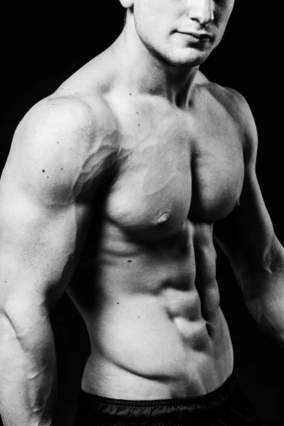 Torso sexy muscolare di giovane uomo sportivo con addominali perfetti da vicino. Bianco e nero isolato su sfondo nero — Foto Stock