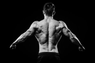 Genç ve zinde vücut geliştirmeci atlet pazı arkadan siyah arka plan üzerine izole görünümü gösterir