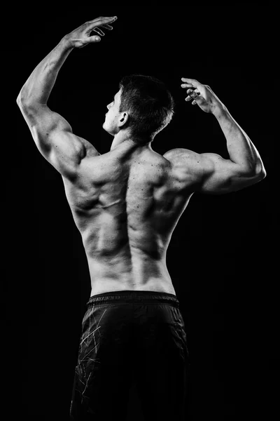 Genç ve zinde vücut geliştirmeci atlet pazı arkadan siyah arka plan üzerine izole görünümü gösterir — Stok fotoğraf