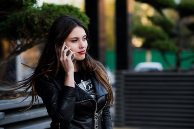 Gülümseyen güzel genç kadın portresi yakın çekim ile arka plan yaz yeşil sokak karşı hareket eden telefon