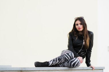 Emin çekici genç kız öğrenci bir eski taş duvarda açık havada oturma