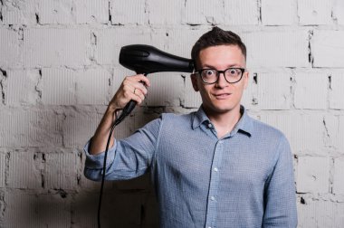 Deli şık delikanlı hairdraier ve gri tuğla duvar komik ifadeler ile