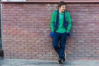 Yeşil t-shirt ceket ve kot yana doğru seyir bir tuğla duvara ortak genç adam