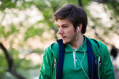 Müzik kulaklık olan genç adam. Hakkında bir şey düşünen kişinin parkta, portre.