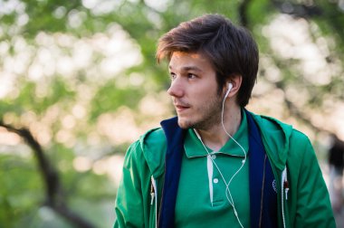 Müzik kulaklık olan genç adam. Hakkında bir şey düşünen kişinin parkta, portre.