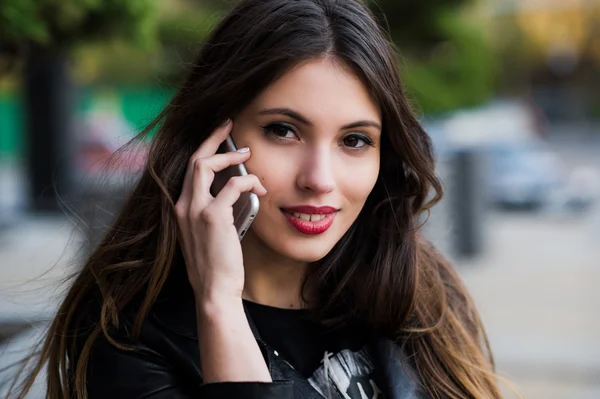 Retrato de una hermosa mujer con una sonrisa blanca perfecta hablando en el teléfono móvil al aire libre — Foto de Stock