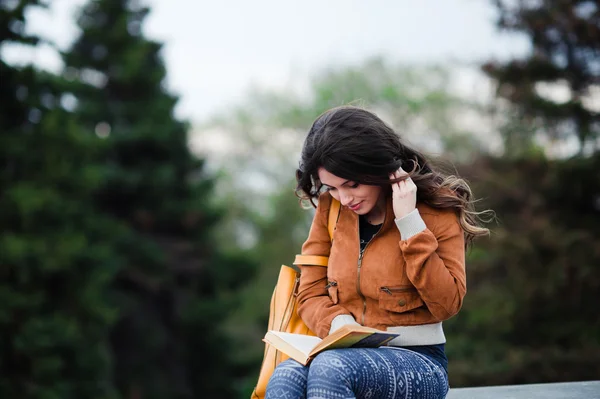 Задумчивая женщина размышляет о книге, которую она читает во время своего свободного времени на весенних каникулах, великолепная молодая женщина мечтает что-то хорошее, сидя в осеннем парке — стоковое фото