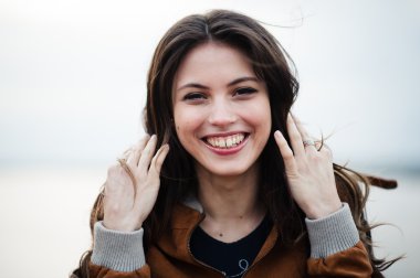 Yakın çekim deri ceket gülümseyen ve arka plan ışığı açık havada duran giyen genç mutlu güzel çekici kadın portresi.