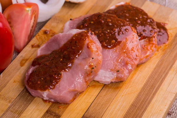 Нарезанные куски сырого мяса для барбекю со свежими овощными помидорами, салат на деревянной поверхности — стоковое фото