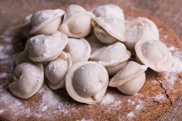 Ongekookt dumplings Pelmeni. Traditionele Russische schotel. Achtergrond van pelmeni neergelegd op een snijplank — Stockfoto