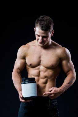 Siyah plastik kavanoz boş beyaz etiket peynir altı suyu proteini holding ve koyu arka plan üzerinde izole eliyle göstererek vücut geliştirmeci