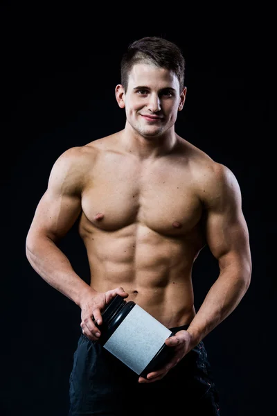 Beautiful young athletic man holding a jar of sports nutrition — Stock Photo, Image