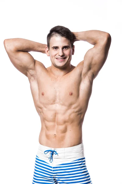 Портрет красивого молодого мускулистого мужчины в купальниках с руками, сложенными над головой, изолированными на белом фоне — стоковое фото