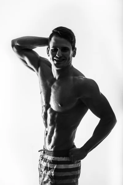 Dark contraste shot jeune musclé fitness homme estomac et bras. Bodybuilder avec des perles d'entraînement à la sueur dans la salle de gym . — Photo