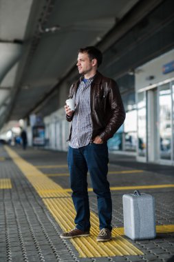 Genç normal adam ayakta bekleyen fincan kahve ve gümüş durumda yakınındaki