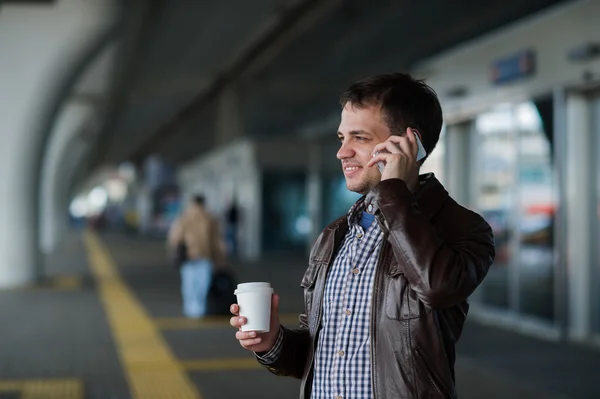 Portrait of a handsome young man stand near the airport waiting for next flight and talking on mobile phone — Stock Photo, Image