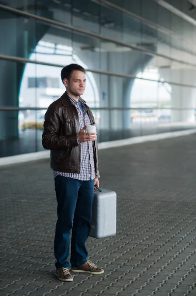 Full length portrait young happy smiling handsome traveller man in 20s leaving arrivals airports lounge terminal building after collecting his baggage with a cup of fresh coffee — Stock Photo, Image