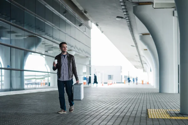 Путешественник ходит с чемоданом на улице возле терминала аэропорта — стоковое фото