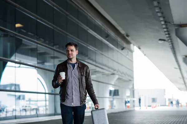 Mannen i flygplatsen håller en väska och promenader med kopp kaffe — Stockfoto